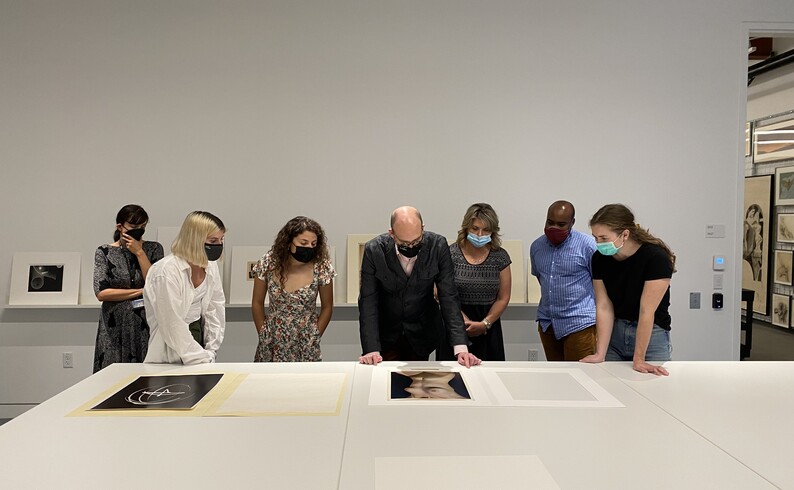 group of people look at artwork on a table