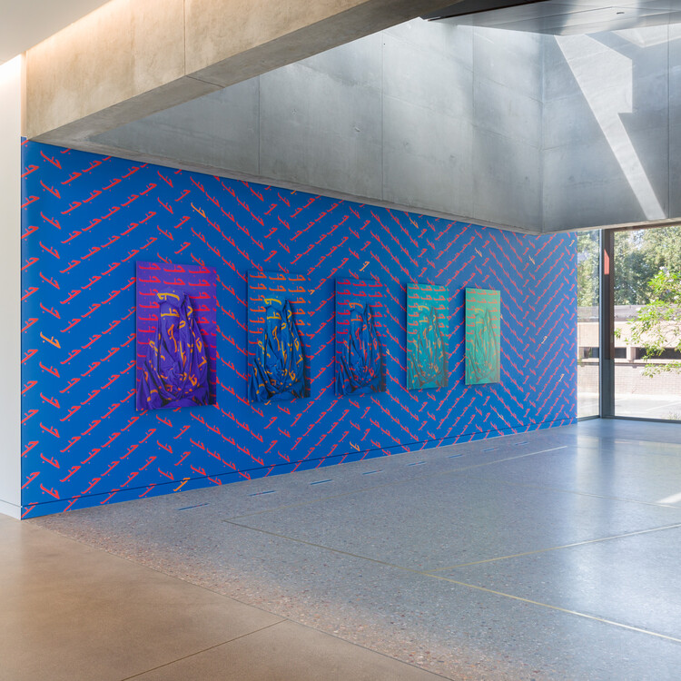 Installation view of Alia Ali's site-specific installation of Love with 5 photographs on blue wall with patterns of Love painted in Arabic