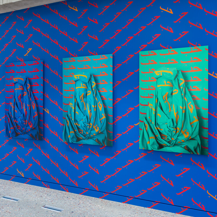 Close up of photographs again blue painted wall with the word LOVE/حب repeatedly