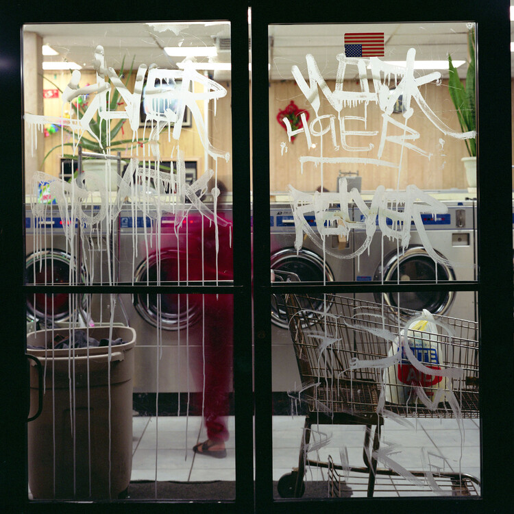 Photograph of a lavanderia with graffiti'ed glass doors