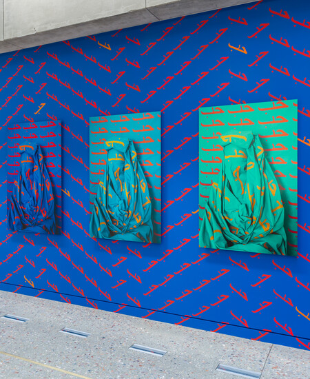 Close up of photographs again blue painted wall with the word LOVE/حب repeatedly