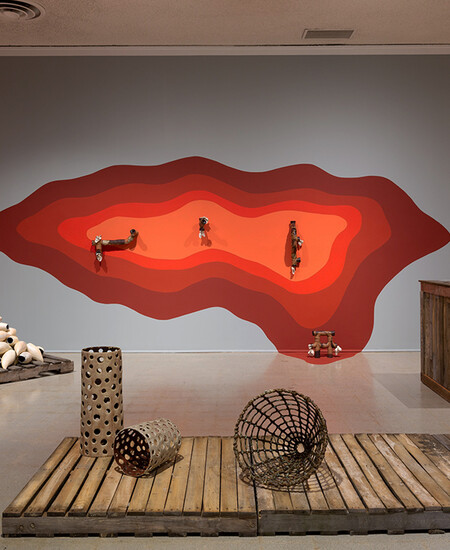 Wavy red painting on wall with ceramic works on ground