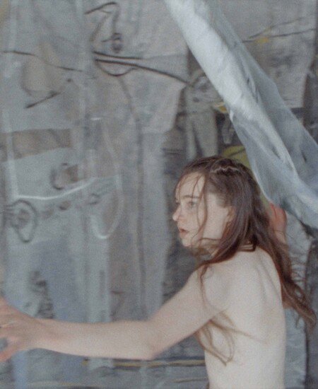 woman in motion holding gauze in front of gray canvas
