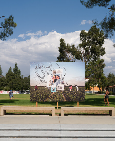 billboard in front of field with trees and clouds. a person riding a bike is about to pass in front of the scene