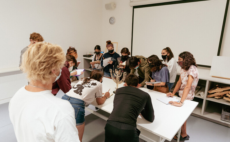 Students surrounding art object for close observation