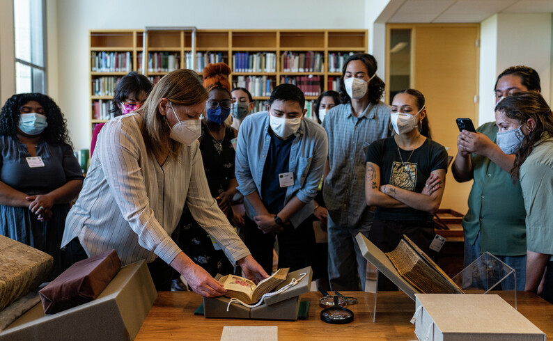 group of people gather around and look at a book