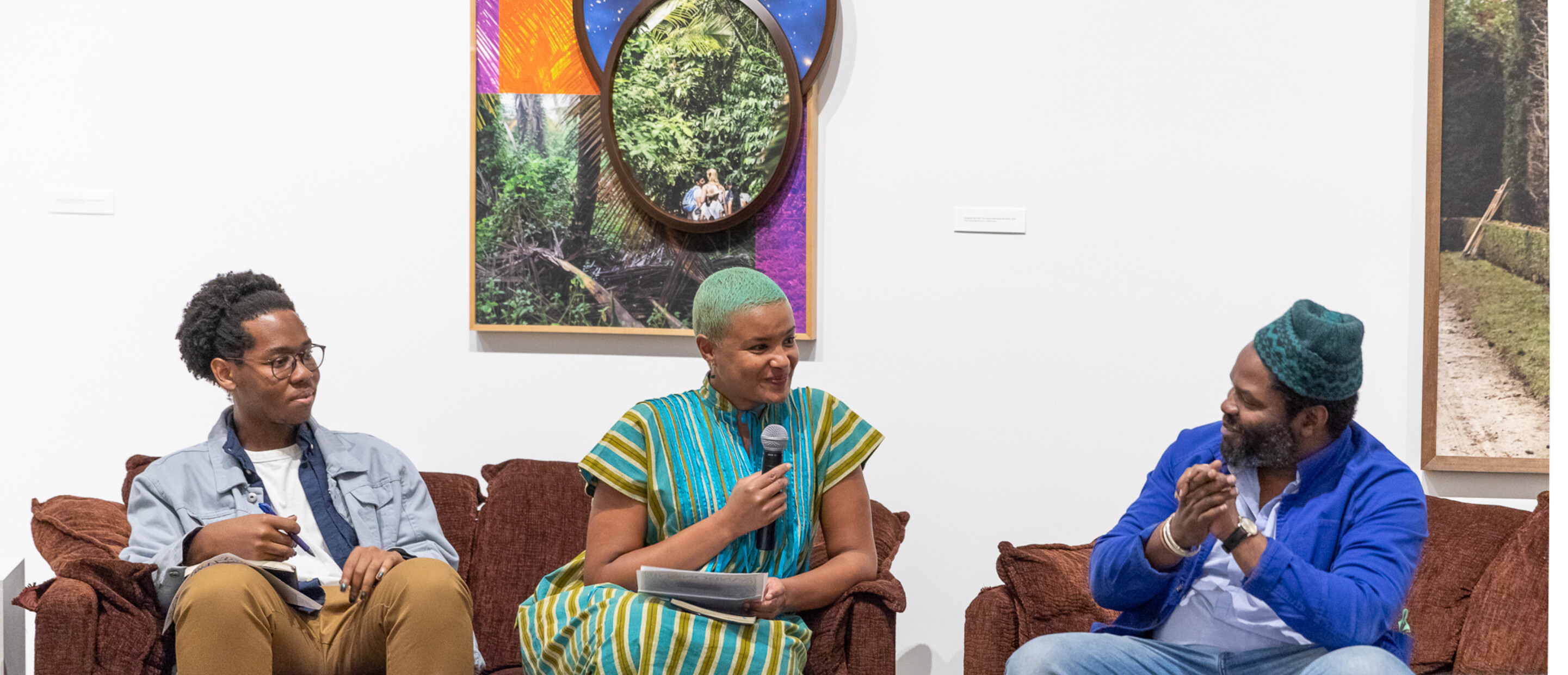 Three people with microphones speaking as part of a panel in a museum gallery