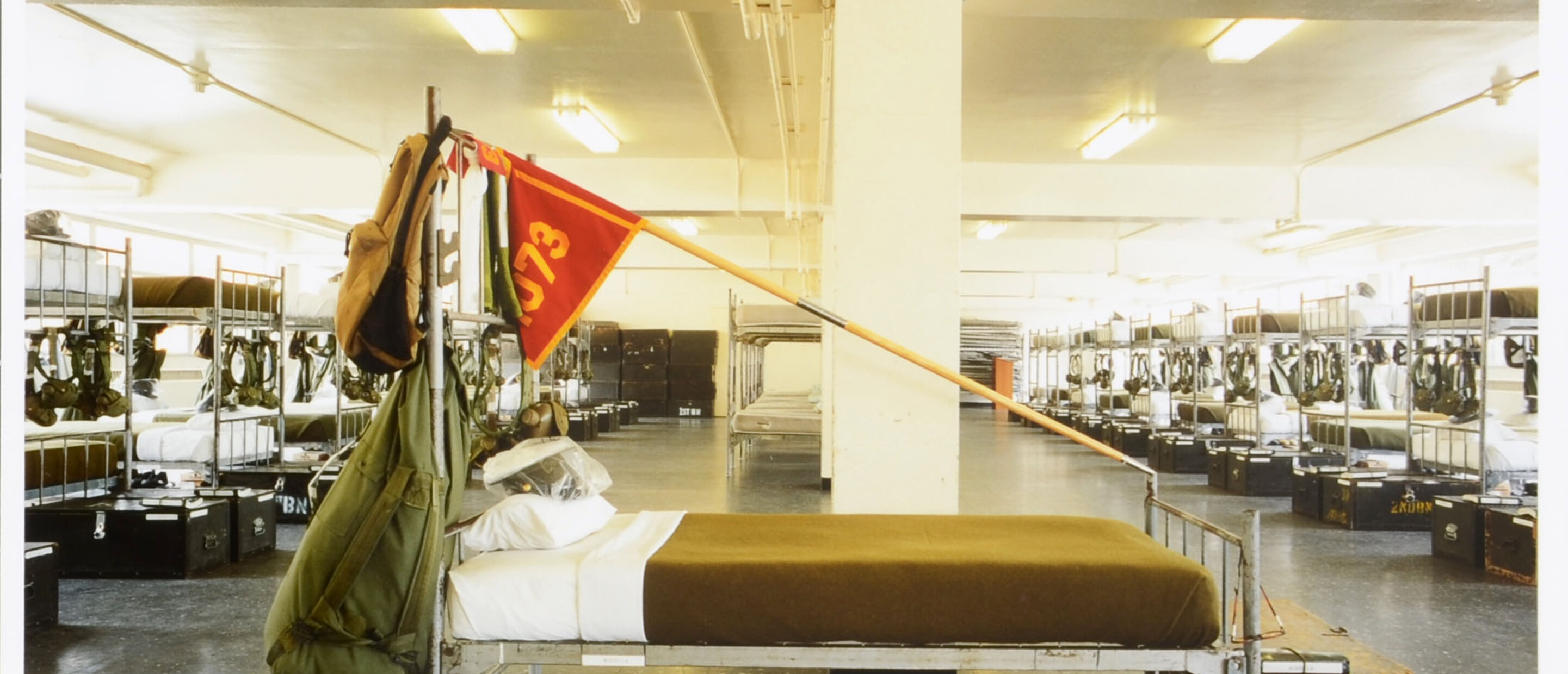 Empty bed with flag overhead with rows of beds behind