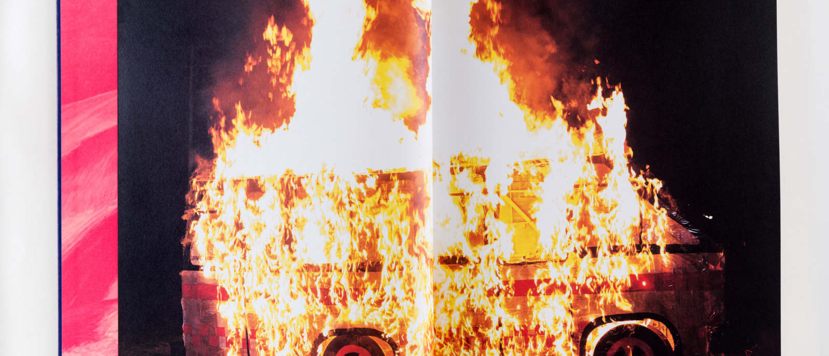 Catalogue spread of photo showing microbus engulfed in flame
