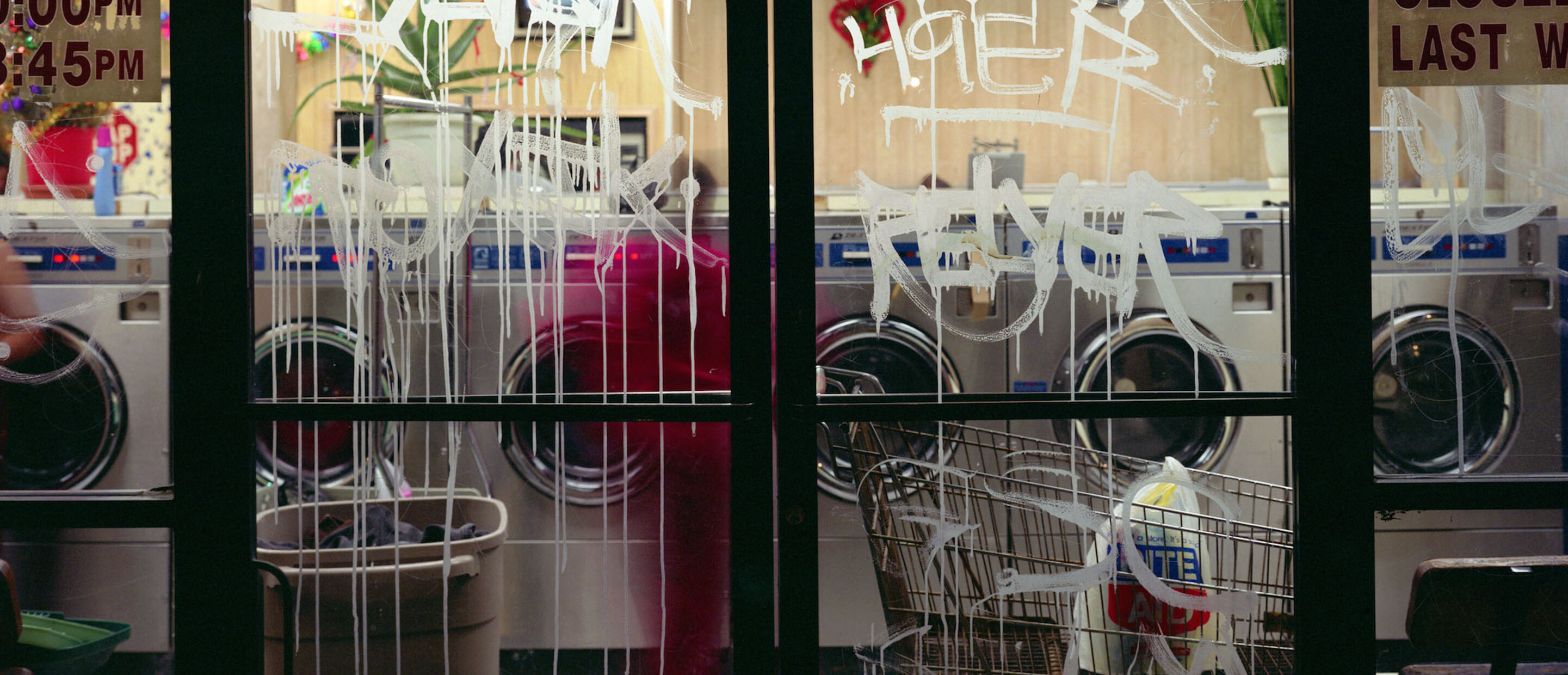 Photograph of a lavanderia with graffiti'ed glass doors