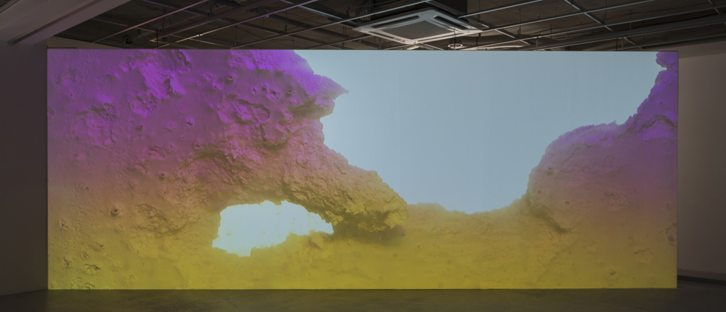 Video installation showing image of geological like landscape in gallery
