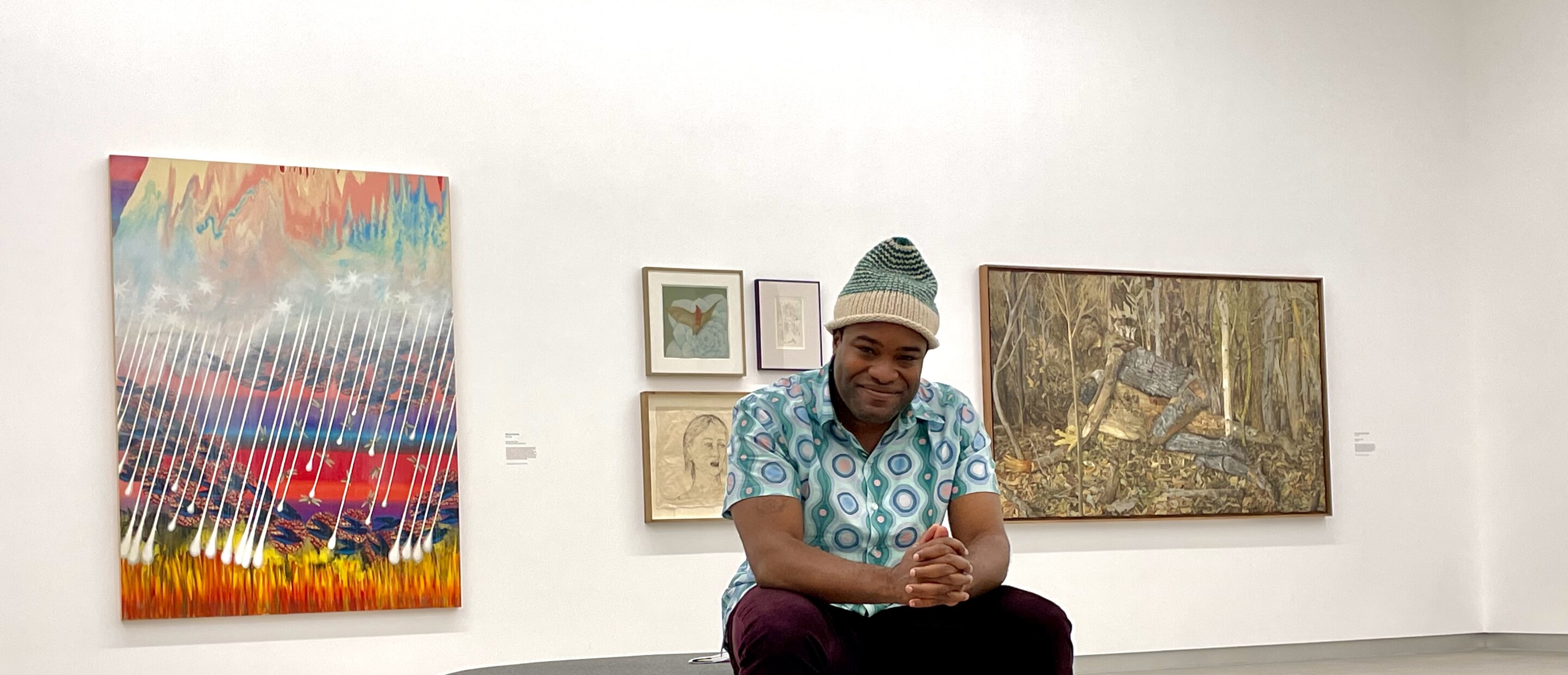 Person sitting in gallery with artworks installed in the background