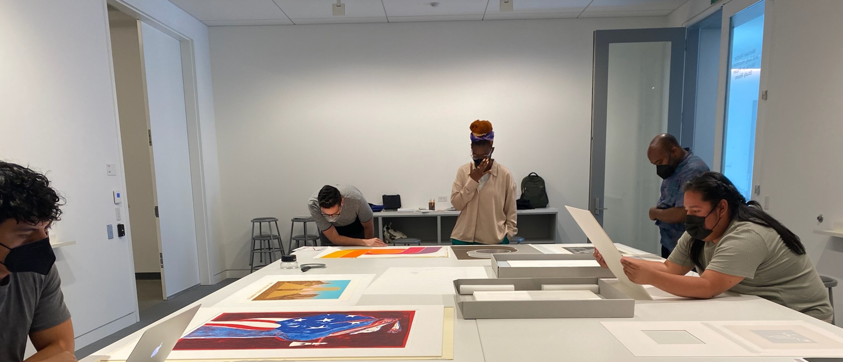 5 people looking at prints on a large table