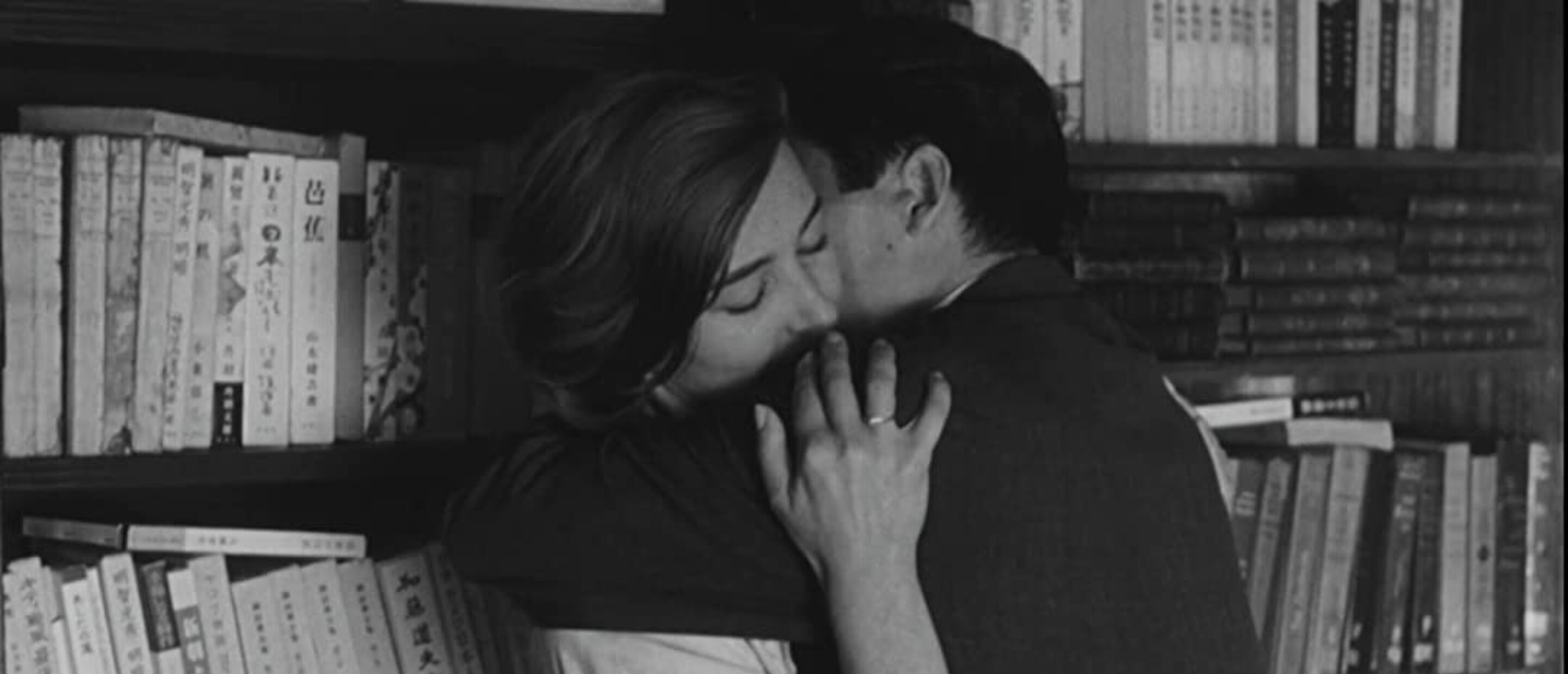 man and woman embrace against bookshelf