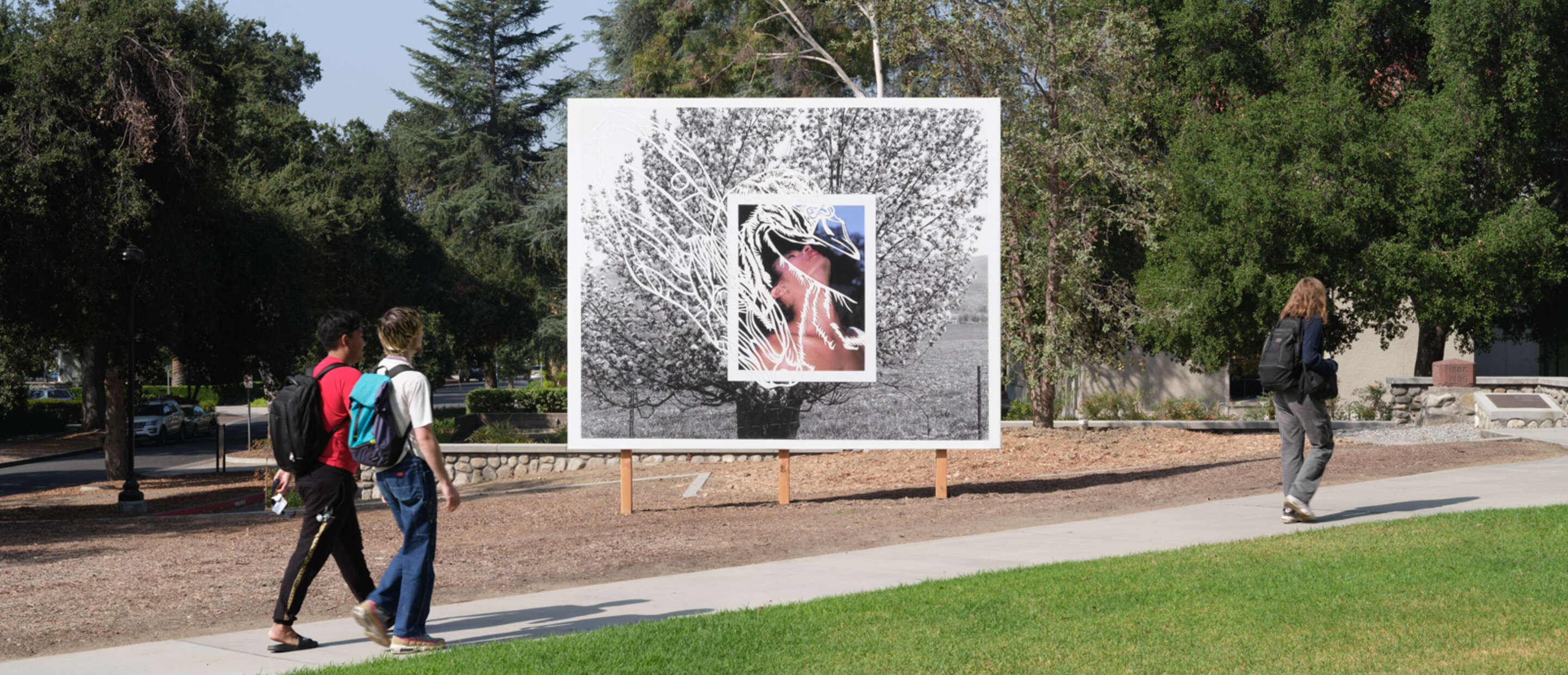 three people walk down path with billboard in the background