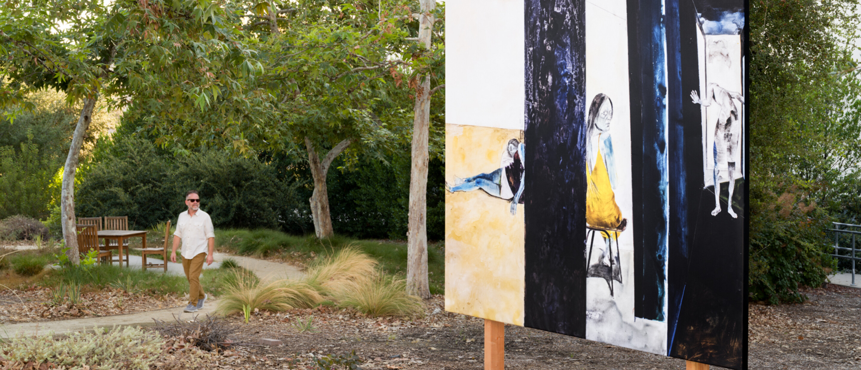 man in white looks at billboard with blue and yellow in a shaded area