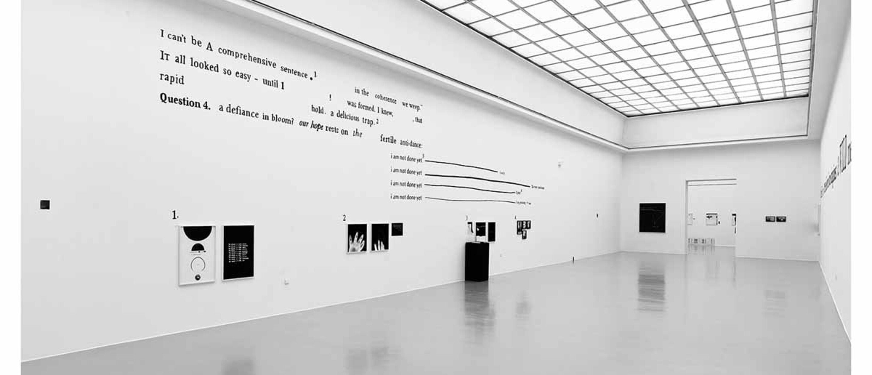 white gallery with black writing on wall and black and white prints