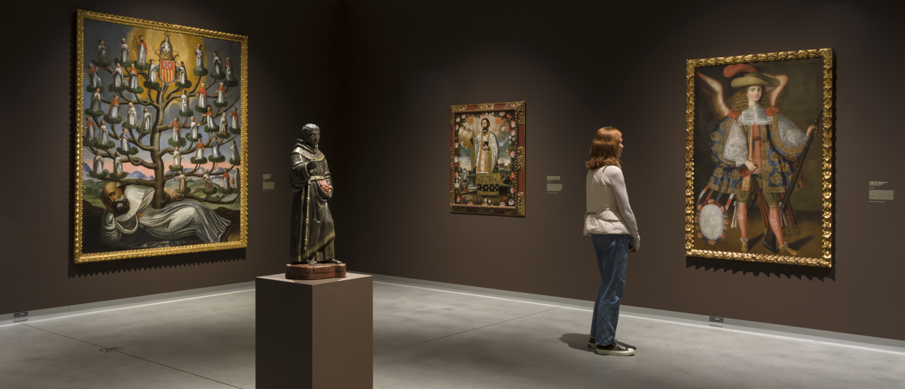 brown gallery with sculpture and large paintings and person