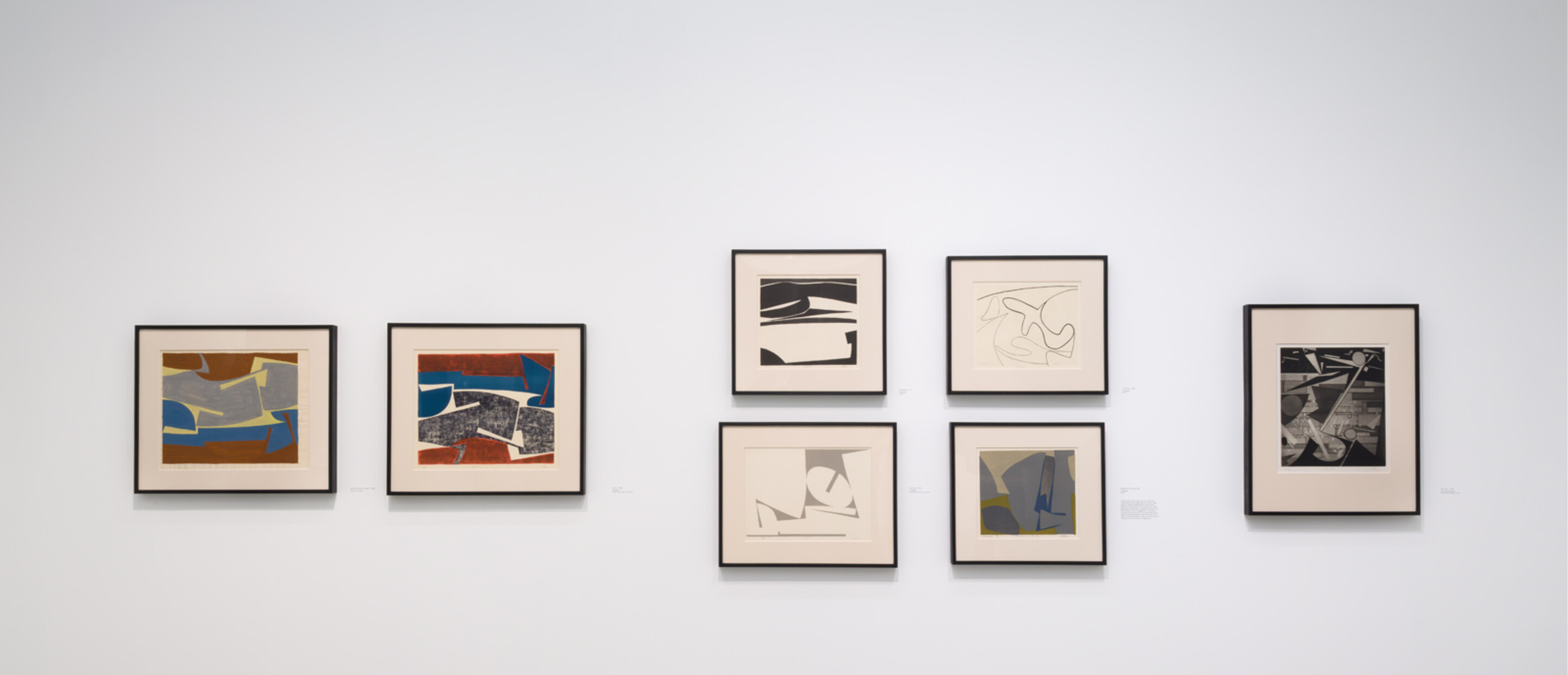 wide shot of framed works on white wall