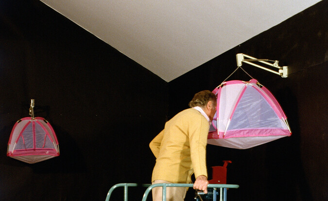 A person looking through a small tent mounted high using a cycle with stairs moving structure