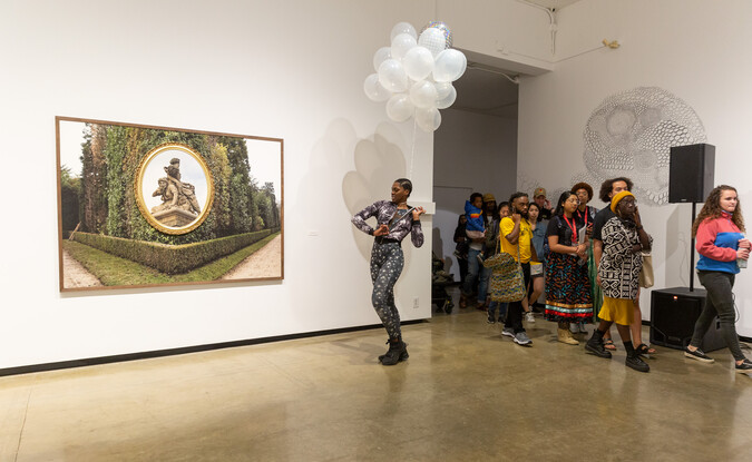Performance artist entering into a gallery with a group of followers behind