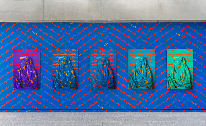 Installation view of Alia Ali's site-specific installation of Love with 5 photographs on blue wall with patterns of Love painted in Arabic