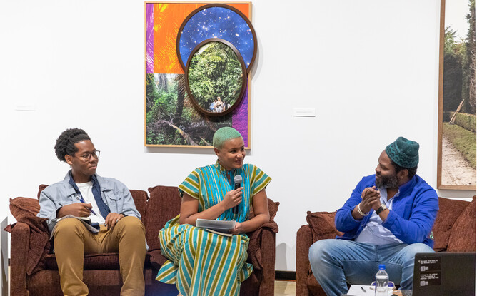 Three people with microphones speaking as part of a panel in a museum gallery