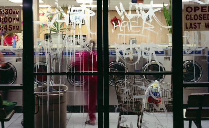 Photograph of a lavanderia with graffiti'ed glass doors