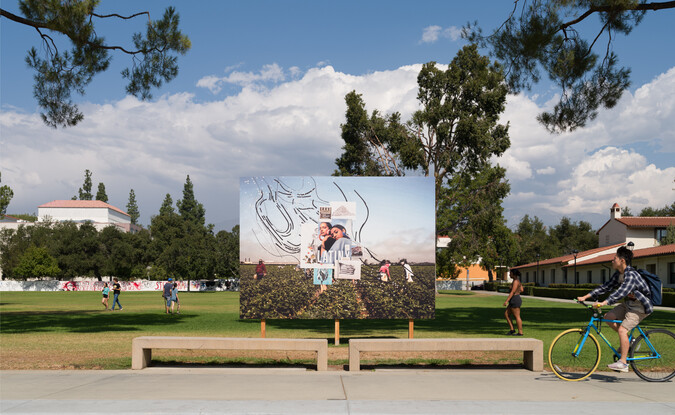 billboard in front of field with trees and clouds. a person riding a bike is about to pass in front of the scene