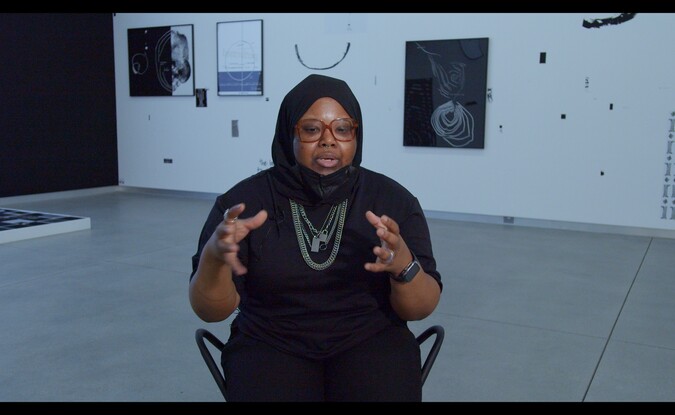 woman wearing all black sits in gallery