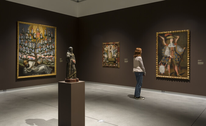 brown gallery with sculpture and large paintings and person