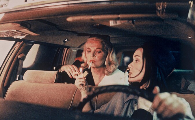 2 women in taxi smoking a cigarette
