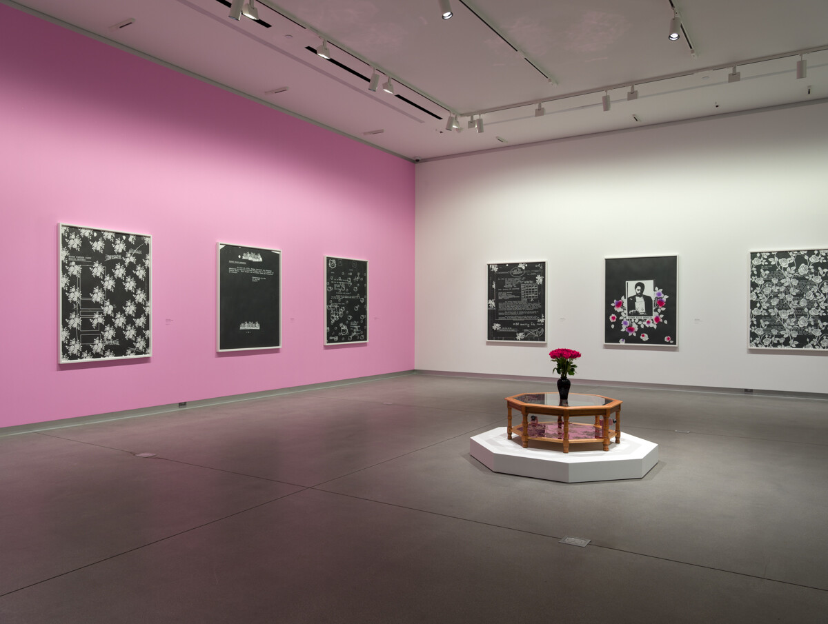 2 wall installation view of art exhibition with 6, 2-dimensional works and centerpiece on platform