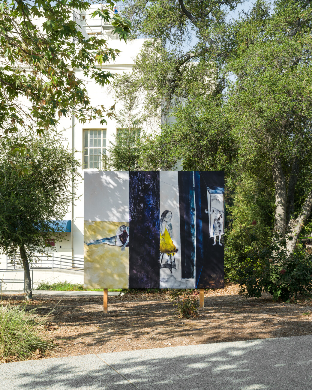 billboard shadowed in dappled light among trees in front of a white building