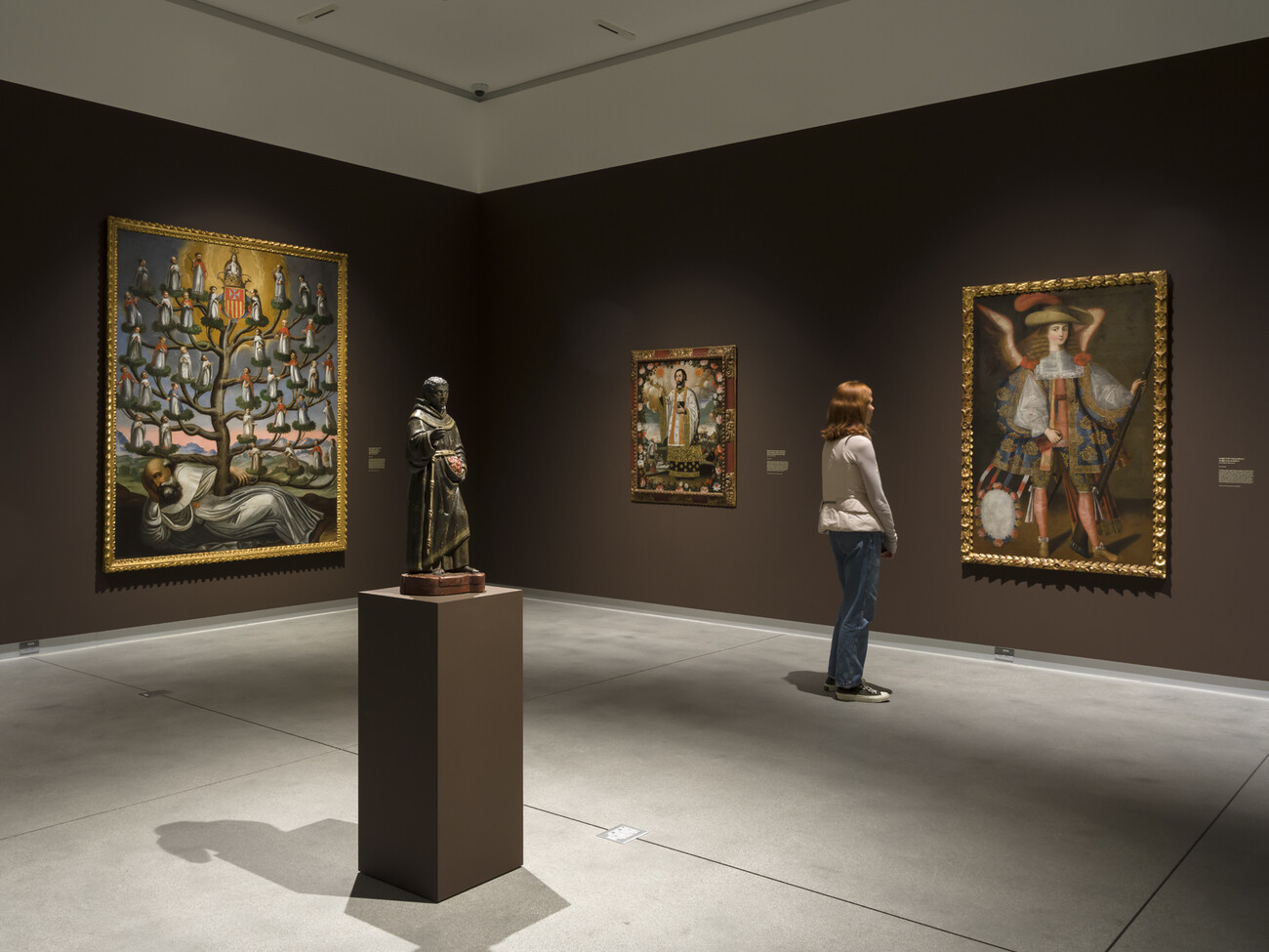 brown gallery with sculpture and large paintings and person