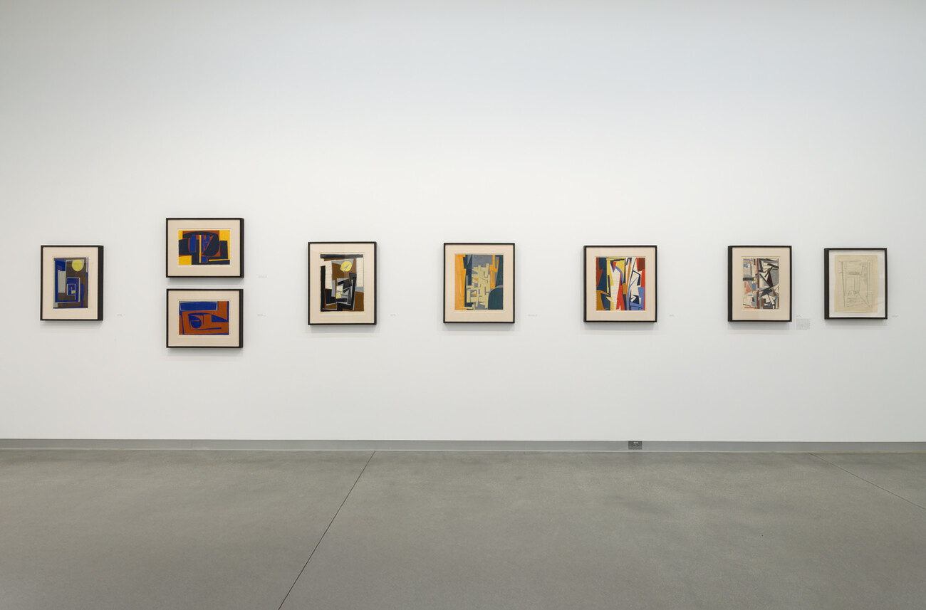 wide shot of framed artworks hung on wall