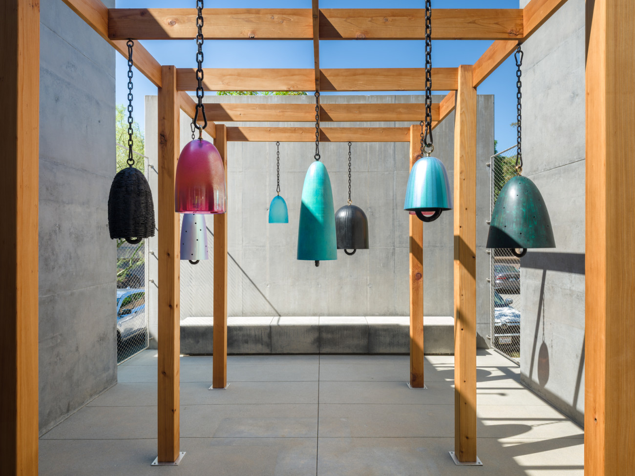 wide shot of colorful bronze and glass bells hanging on outdoor pergola