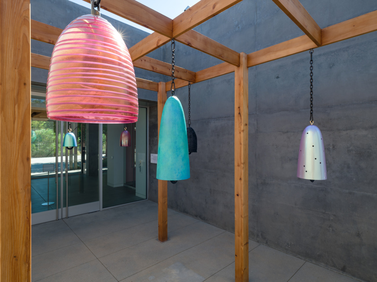 medium shot of glass and bronze bells with various finishes on outdoor pergola