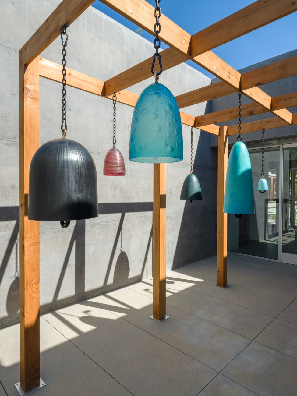 medium shot of a group of bronze and glass bells hanging in an outdoor pergola