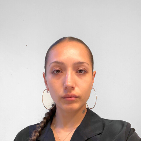 Woman with hair pulled back in a braid with black shirt and hoop earrings