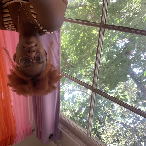 Person in front of window with purple pink and orange curtains
