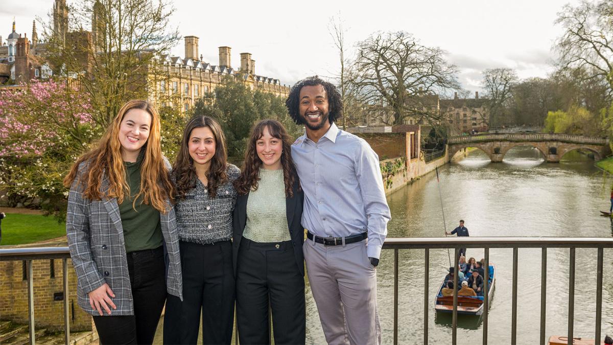 Four Pomona College alumni standing on a bridge over the River Cam in Cambridge, England