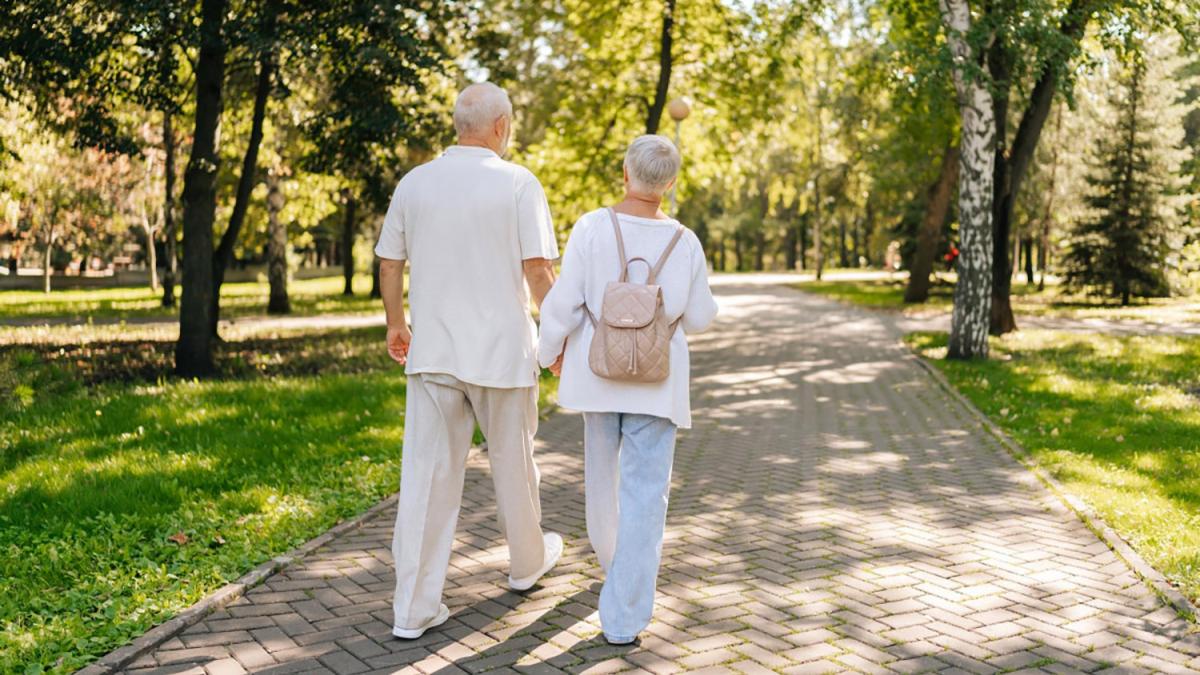 Retired couple walking through park