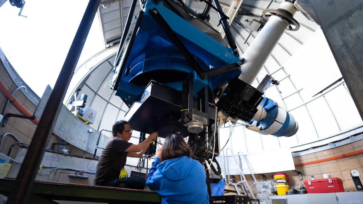 Two people work on a telescope