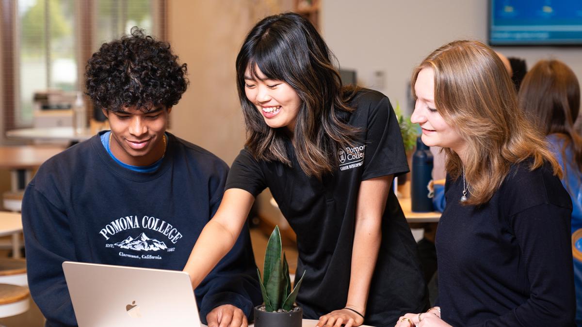 students and professor looking at a laptop