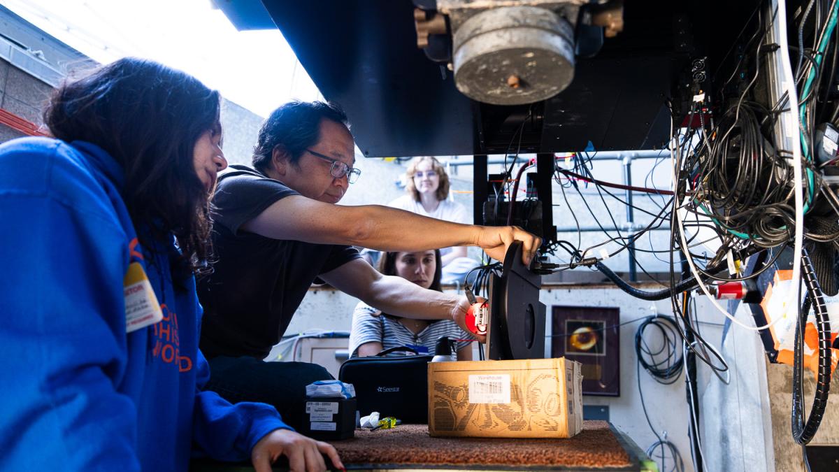 professor and students working on a telescope