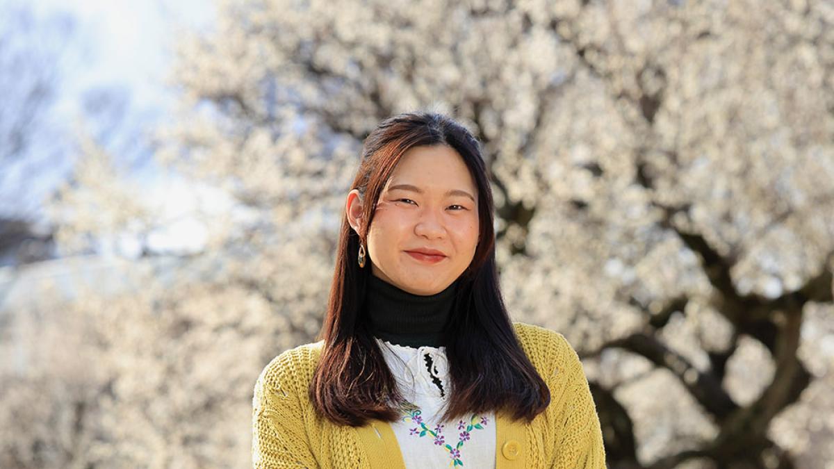 Japanese Language Resident Wako Sato standing in front of cherry blossoms