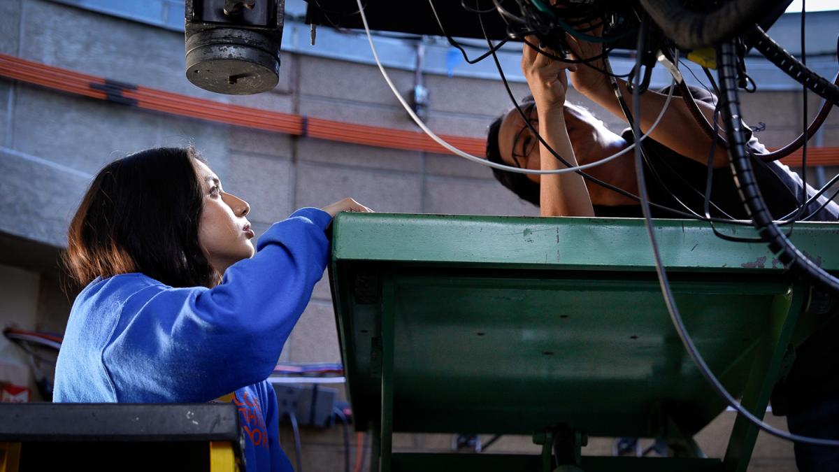 A student and professor work on a telescope