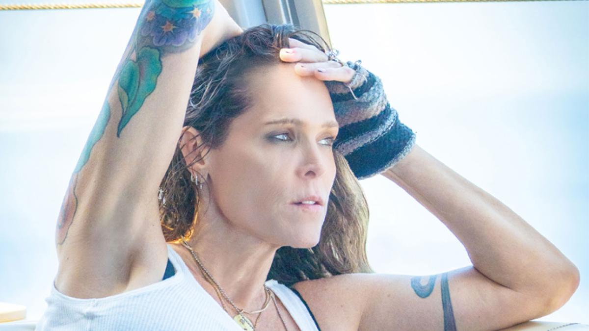 A soft pastel portrait of Beth Hart, angstily gazing away from the camera towards the left side, her arms up holding her hair back.