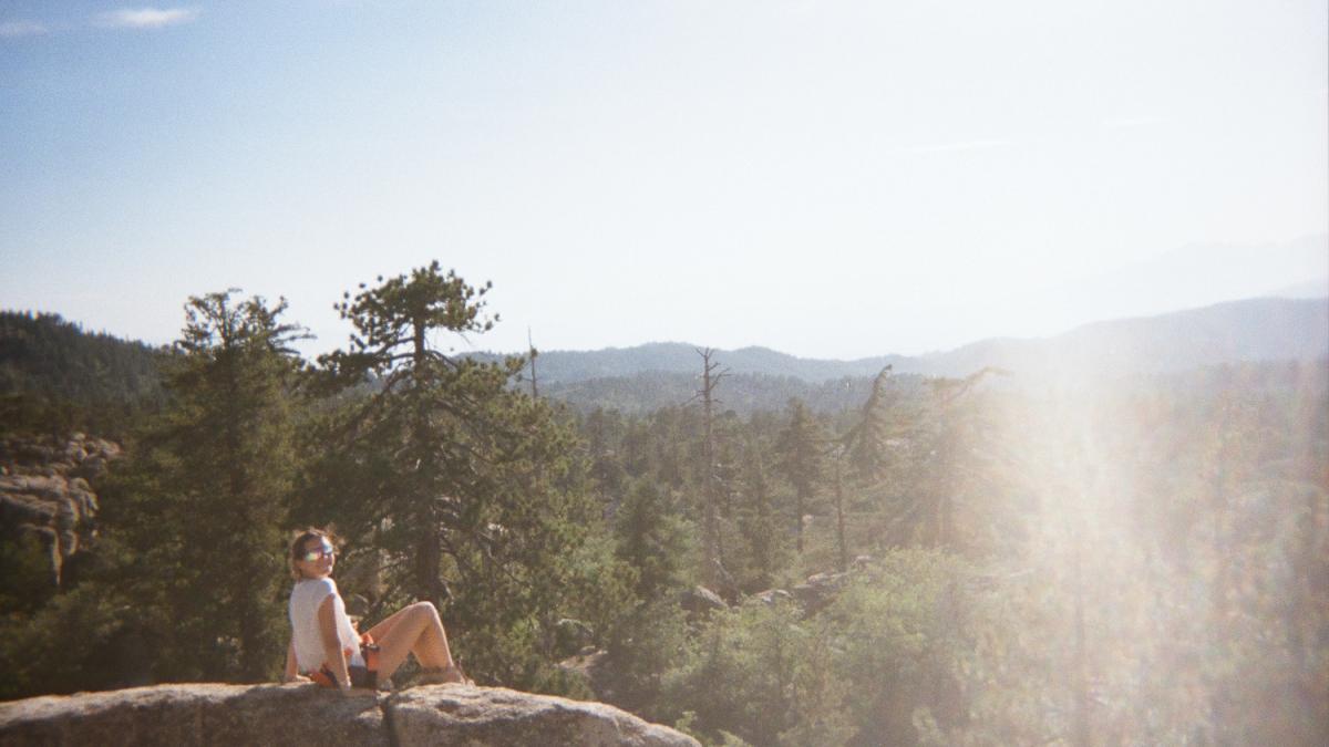 A students sits on a mountain ledge